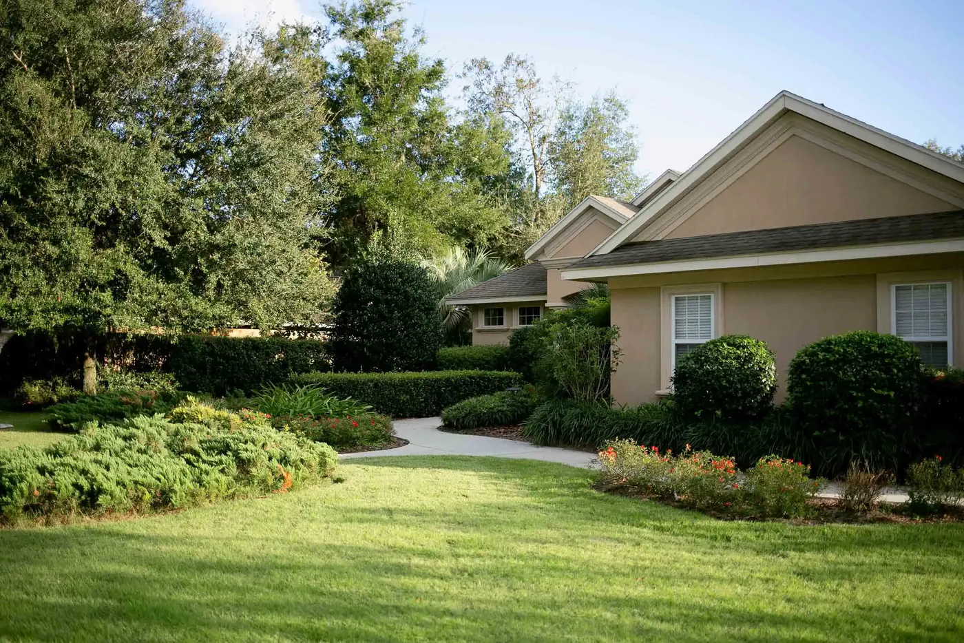 Home with a full lawn, clipped hedges and mature oaks