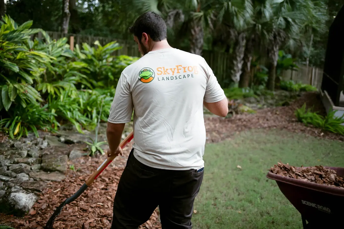 SkyFrog crew member raking fresh mulch into a bed